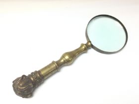 A Victorian magnifying glass with heavy brass hand