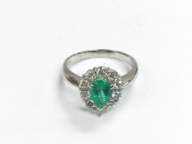 A platinum ring set with a pear shaped emerald wit
