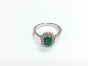 An 18ct white gold, oval emerald and diamond clust