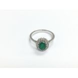 An 18ct white gold, oval emerald and diamond clust