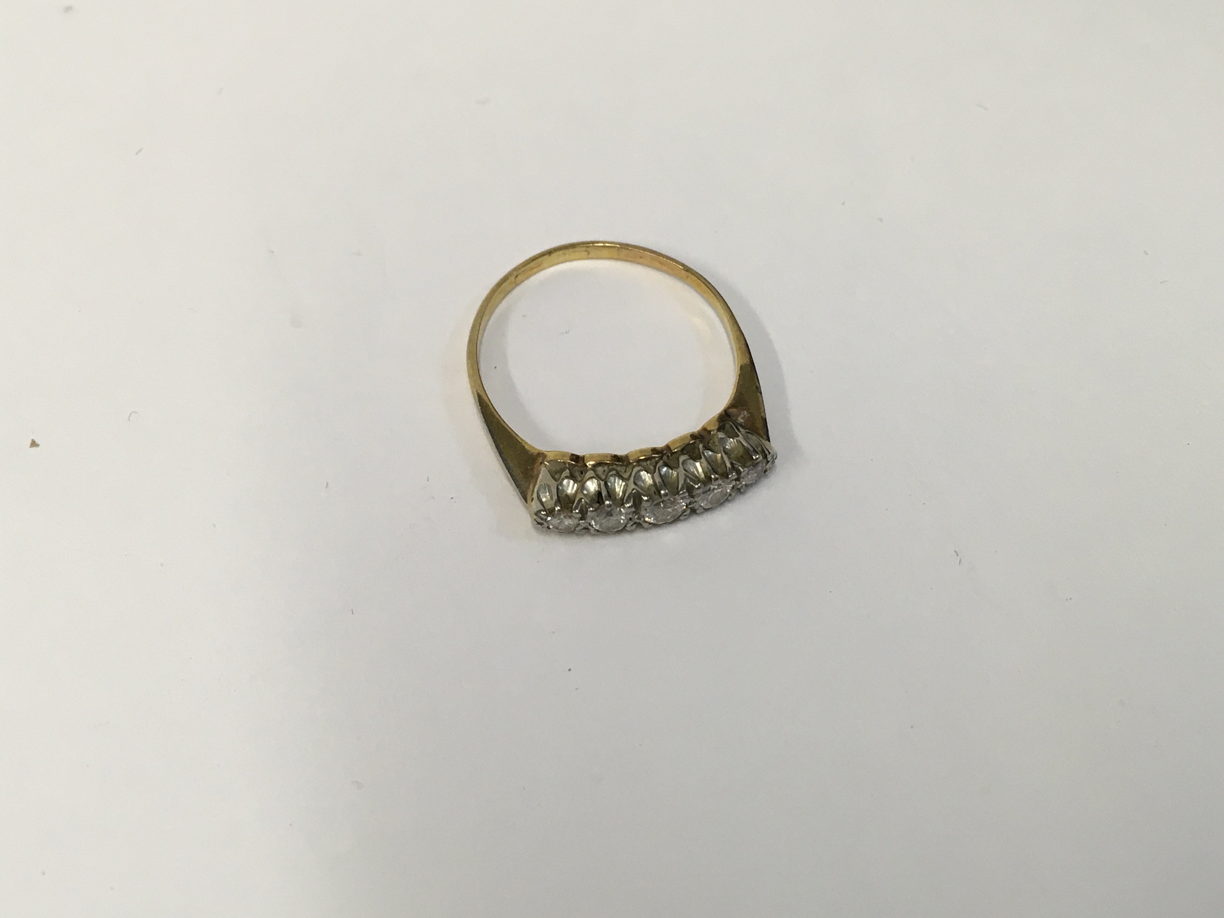 An unmarked gold ring set with a row of five diamo