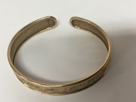 A 9carat gold bangle with floral engraved pattern
