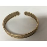 A 9carat gold bangle with floral engraved pattern