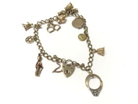 A 9ct gold charm bracelet with assorted charms. To