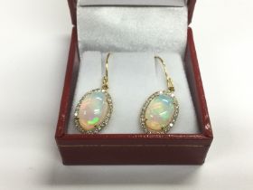 A pair of drop earrings set with oval cabochon opa