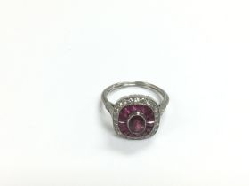 A platinum ring set with a central oval ruby surro