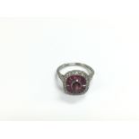 A platinum ring set with a central oval ruby surro