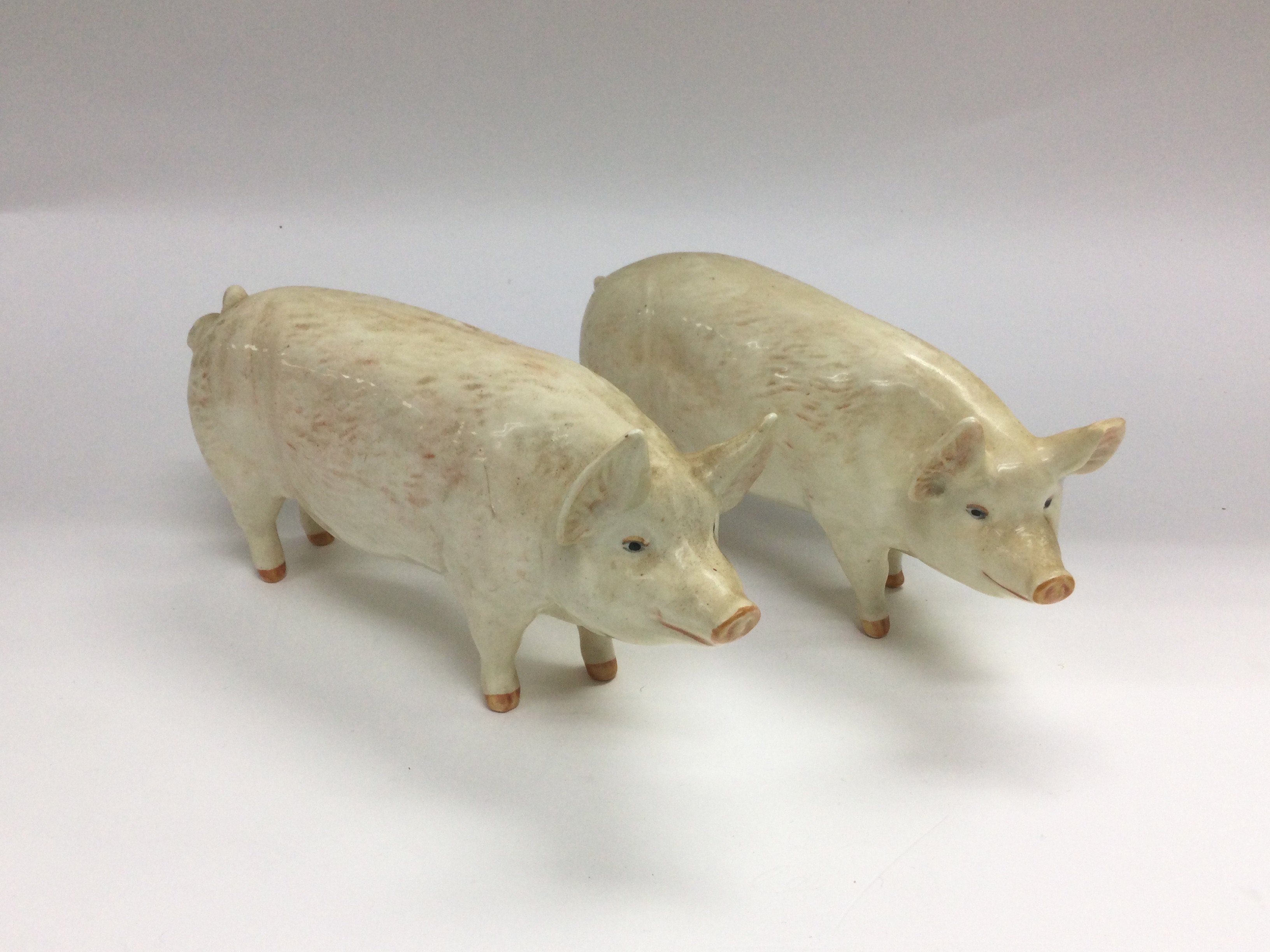 Two Beswick figures of pigs, one has a chipped ear