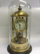 A brass anniversary clock under a glass dome, appr