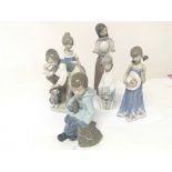 A collection of Lladro figures a boy seated with a