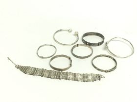 A collection of silver bangles and a gate bracelet