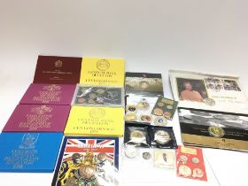 A collection of coin sets and commemorative coins.