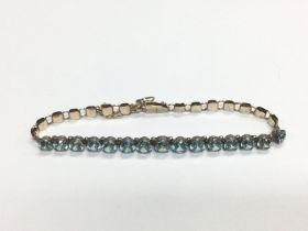 A gold bracelet set with a row of blue zircons, ap