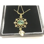 Floral pendant in yellow metal set with oval emera