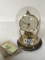 A German made brass anniversary clock under a glass dome with key.