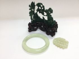 A jade bangle and toggle plus a carved stone ornam