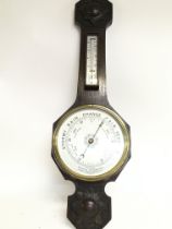 An oak barometer with carved wooden design , appro