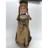 A cloth doll in Victorian style dress under a glas