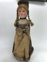 A cloth doll in Victorian style dress under a glas