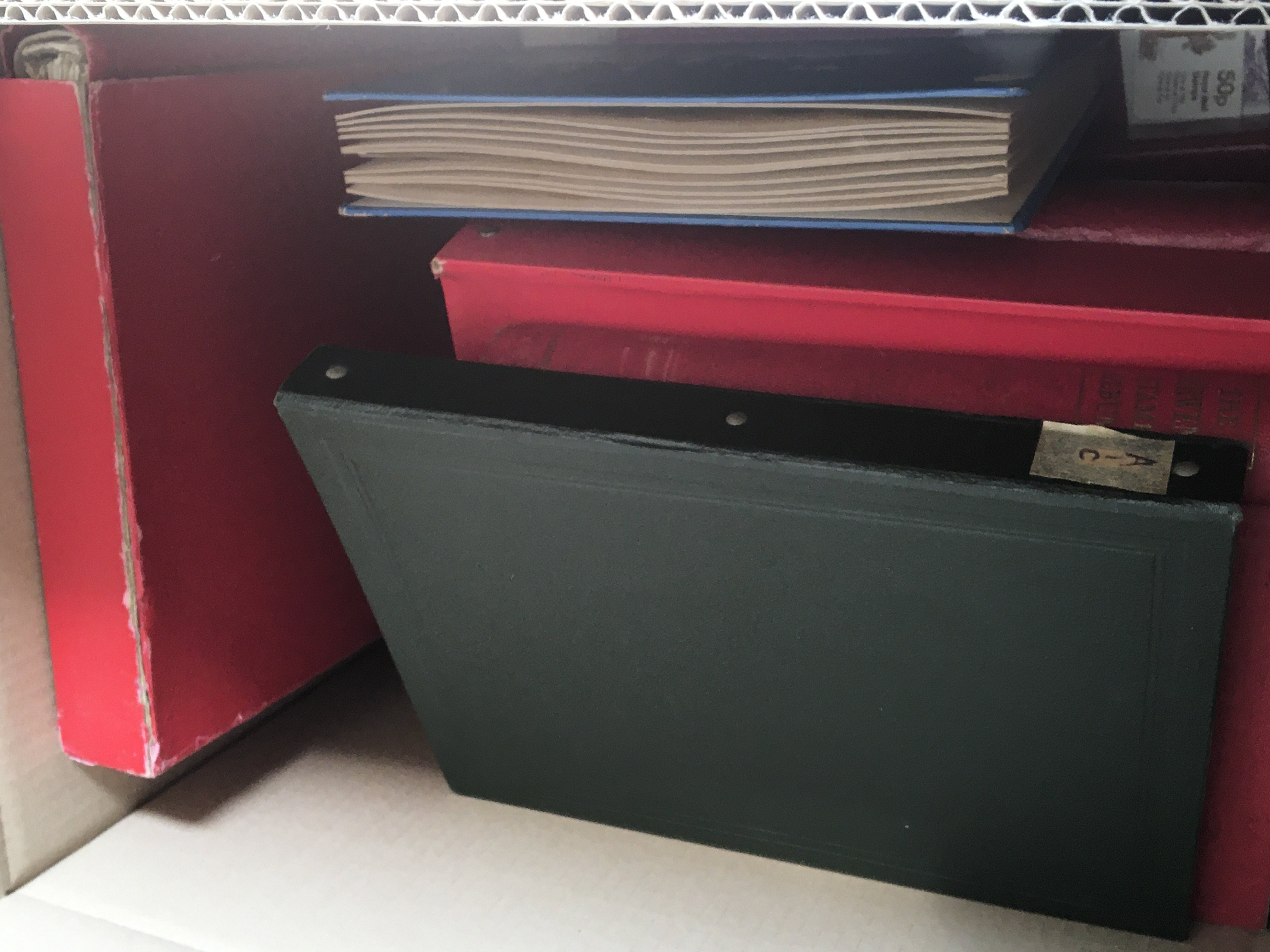 A box containing a quantity of red albums containi