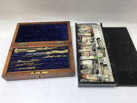 A boxed drawing set and a box of water colours.
