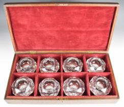 A set of eight faceted cut glass table salts with star cut bases, in fitted oak case.