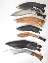 Three kukri knives, all with scabbards, two with kardas and chakmaks, together with a wooden