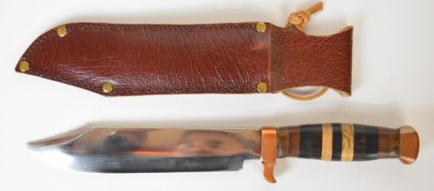 Bowie type knife with banded wooden grip, copper guard and pommel, 18cm blade and leather sheath.