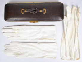 A leather and brass concertina expanding glove box with knotted handle, braided wire mounts, silk