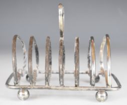 George V hallmarked silver seven bar toast rack with heart shaped hoops and handle, raised on ball
