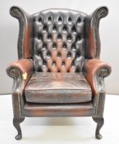 Brown leather Chesterfield wing back armchair raised on cabriole legs, height 105cm