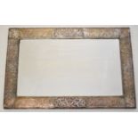 Arts & Crafts copper framed mirror with hammered and relief moulded decoration and bevelled glass