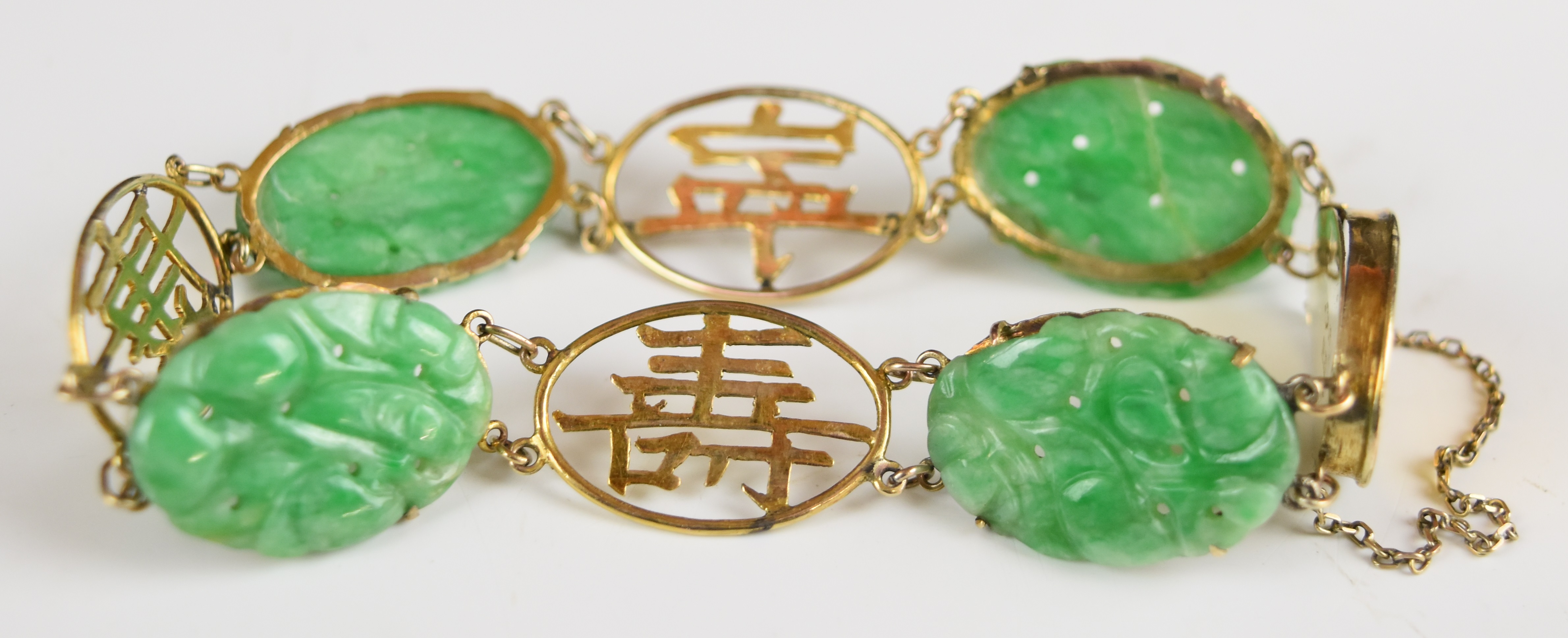 A 9k gold Chinese bracelet set with carved jadeite panels and pierced character links, 12.1g