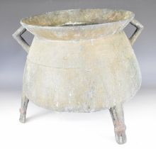 Chinese bronze twin handled cauldron raised on three legs, 27cm in diameter.