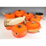 Ten items of Le Creuset cast iron cook ware in Volcanic Orange, to include lidded saucepans, milk