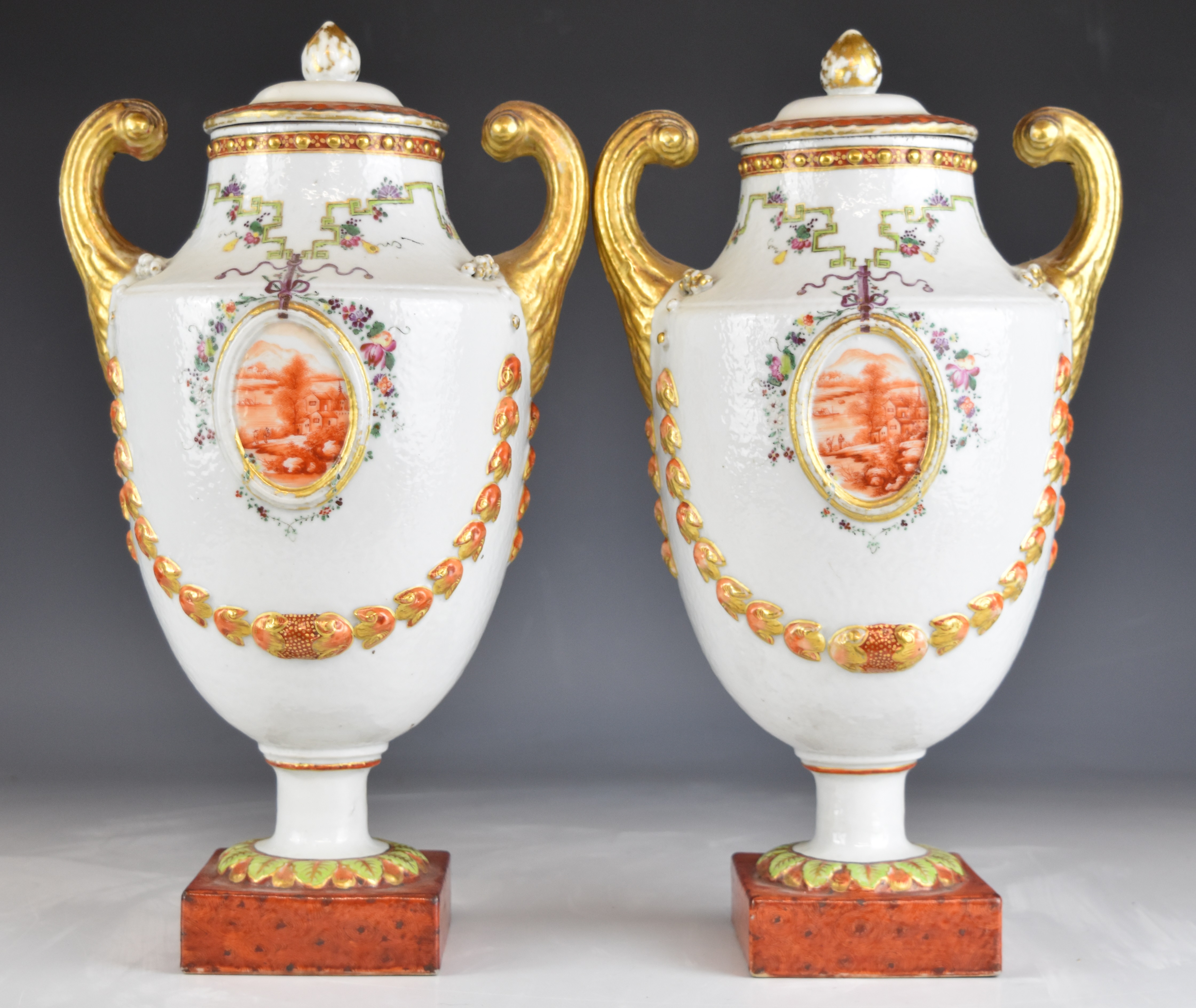 A pair of Chinese covered twin handled pedestal urns with relief moulded swags and landscape