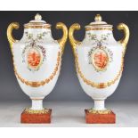 A pair of Chinese covered twin handled pedestal urns with relief moulded swags and landscape