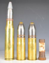 Three brass shells, all with projectiles, tallest 26cm and a steel plug with label 'steel plug