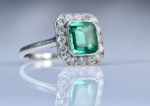 Art Deco platinum ring set with an emerald cut emerald of approximately 1ct surrounded by 16 round