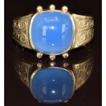 A 9ct gold ring set with a blue agate cabochon, with engraved decoration to the shoulders, 3.6g,