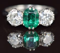 A platinum ring set with an emerald cut emerald of approximately 1.1ct and two old cut diamonds of