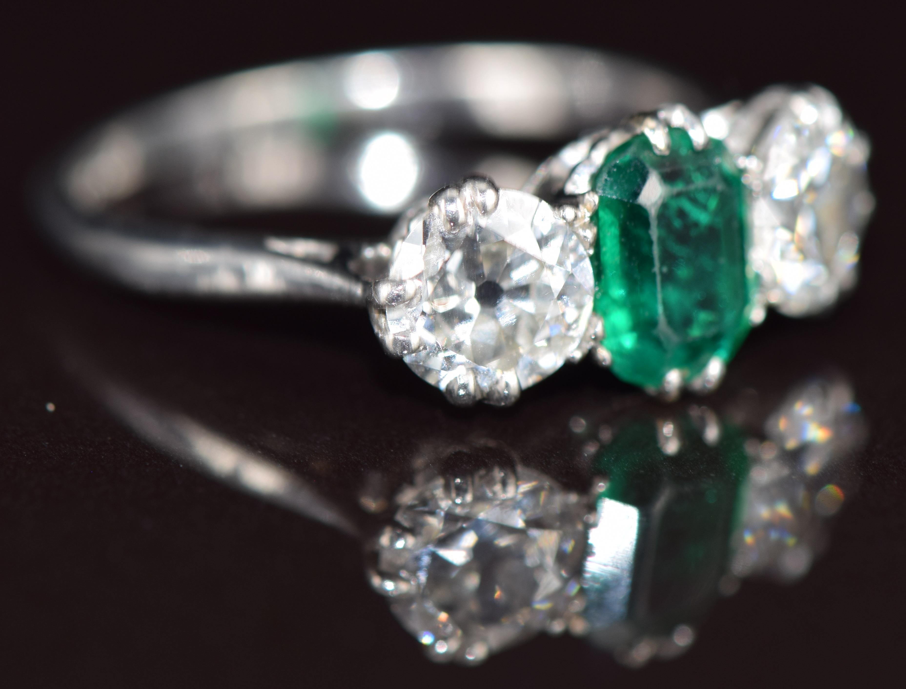A platinum ring set with an emerald cut emerald of approximately 1.1ct and two old cut diamonds of - Image 2 of 3