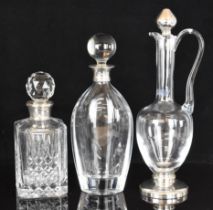 Three hallmarked silver mounted glass items comprising two decanters and a jug, the jug in