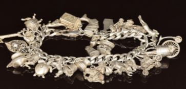 A silver charm bracelet with over 30 charms including Champagne, elephant, boat, etc, 96g