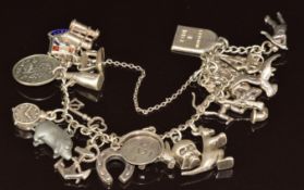 A silver charm bracelet with twenty eight silver charms including Champagne, horseshoe, kangaroo,