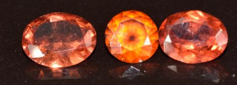 Two loose oval cut Malaya garnets of approximately 1.2ct & 1.3ct and a loose round cut Malaya garnet