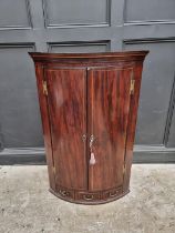 A George III mahogany chequer strung bowfront hanging corner cupboard, 113cm high.