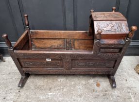 An antique carved oak panelled child's crib, on rocker base, 92.5cm wide.