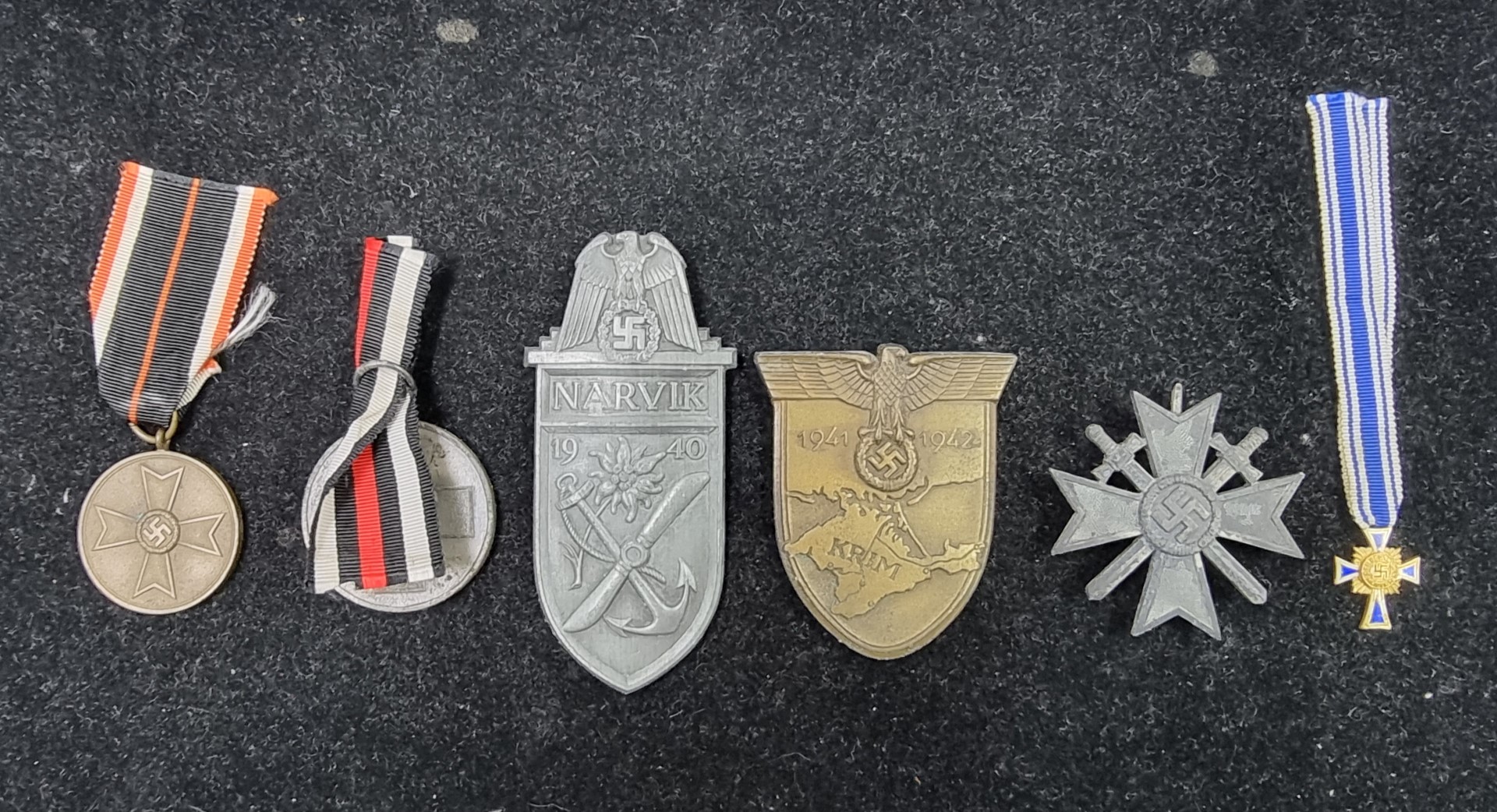 A group of six German WWII medals and badges; to include a Narvik shield; a Crimea shield and a 1939