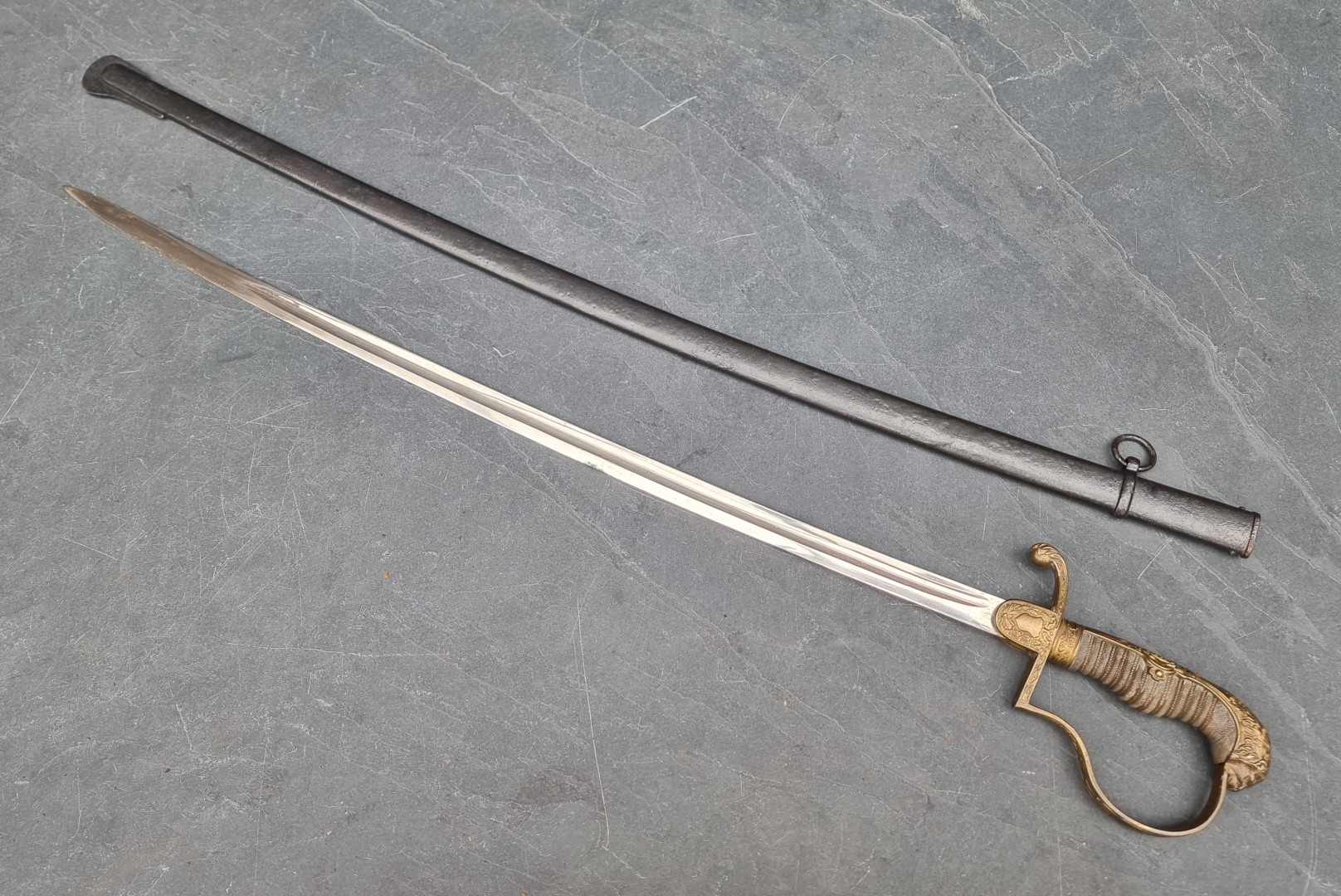 A German Imperial officer's lionhead sabre and steel scabbard, having 76cm fullered blade.